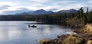 A calm lake with mountains in the background and a person in a boat.