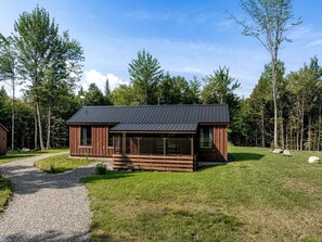 A cabin with a gravel path leading to it, surrounded by trees.