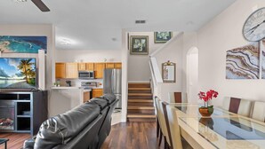 A modern kitchen with wooden cabinets, a stainless steel refrigerator, and a flat-screen TV. - Charming 4/3 Home in Regal Palms Resort (Davenport)