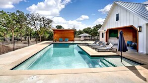 A swimming pool with lounge chairs and a wooden structure. - Luxury Cabin for Four for Texas Glamping Retreat (Wimberley)