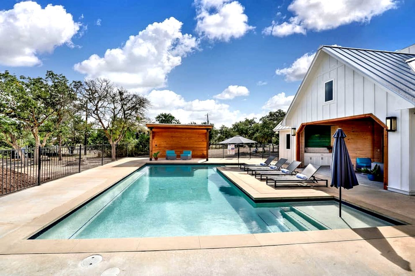 Une piscine avec des chaises longues et une structure en bois.