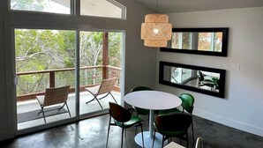 A modern interior with a round table, chairs, a hanging light fixture, and large windows. - Luxury Cabin for Four for Texas Glamping Retreat (Wimberley)