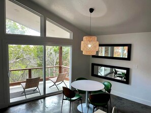 Un interior moderno con una mesa redonda, sillas, una lámpara colgante y ventanas amplias.