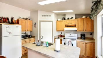 A kitchen with wooden cabinets, a refrigerator, a stove, and a microwave.