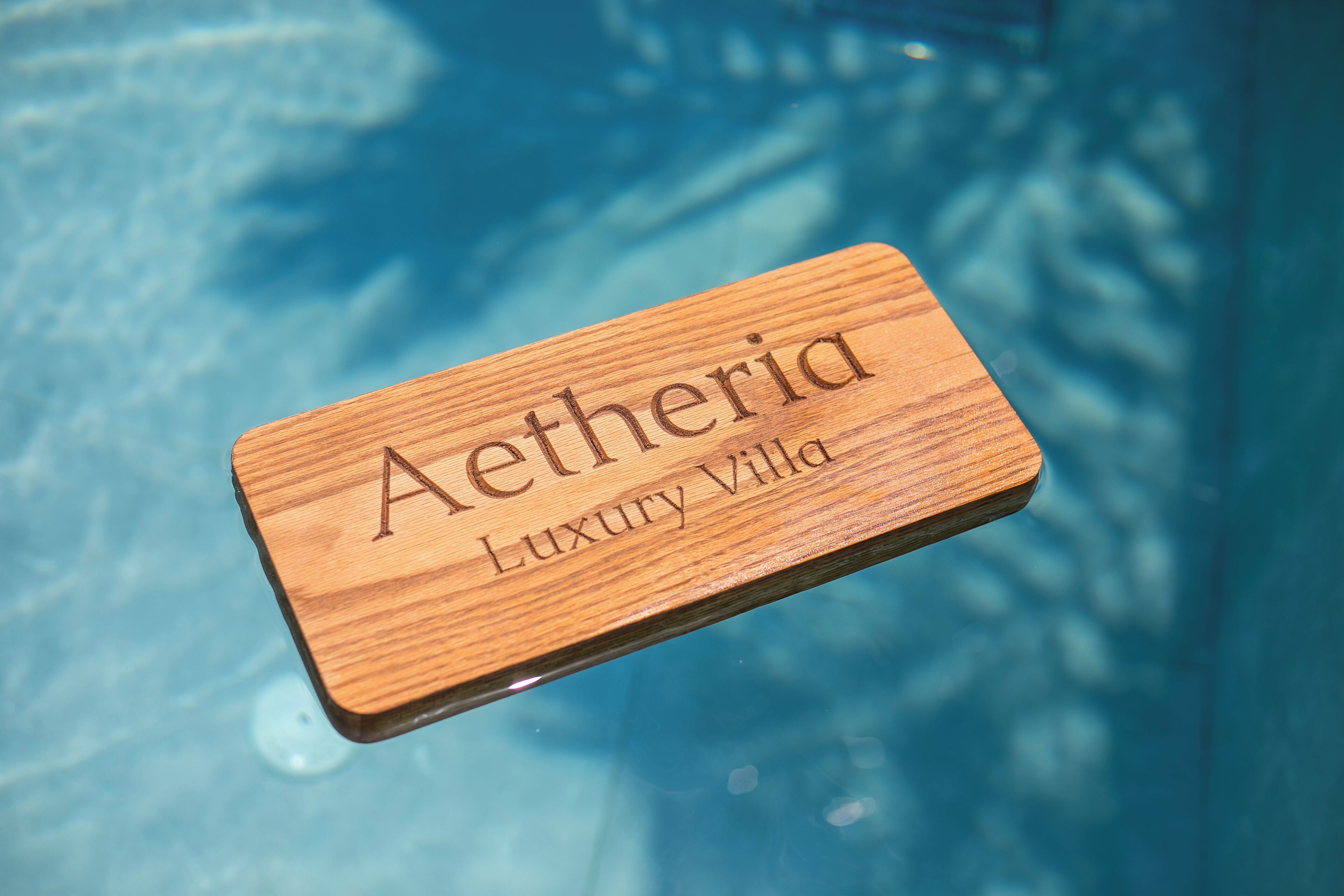 Une plaque en bois portant l’inscription gravée « Aetheria Luxury Villa ».