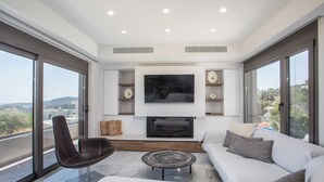Uma sala de estar moderna com televisão de tela plana, lareira, sofá e poltrona.