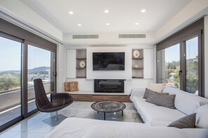 Ein modernes Wohnzimmer mit Flachbildfernseher, Kamin, Sofa und Sesseln.
