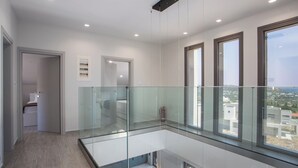 Um interior moderno com varanda de vidro, piso de madeira e vista para a cidade.