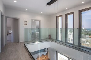 Ein modernes Interieur mit Glasbalkon, Holzboden und Blick auf die Stadt.