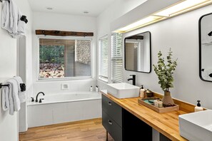 A modern bathroom with a bathtub, two sinks, a wooden vanity, and a large mirror. - Spectacular Rental with Breathtaking Mountain Views in Arizona (Sedona)