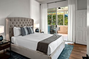 A bedroom with a large bed, a nightstand, a lamp, and a view of a balcony with outdoor furniture. - Spectacular Rental with Breathtaking Mountain Views in Arizona (Sedona)