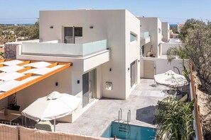 A modern building with a pool, outdoor seating, and a view of the sea. - Aura Luxury Villas Lyra, Villa (Rhodes)