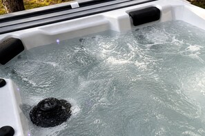 Un jacuzzi con agua, un objeto negro y un exterior blanco.