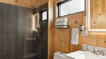 A wooden-paneled bathroom with a shower, toilet, and vanity.