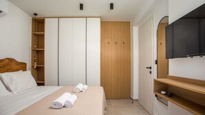 A bedroom with a bed, two rolled towels, a wardrobe, a TV, and a small shelf. - Aura Luxury Villas Anasa, Villa (Rhodes)