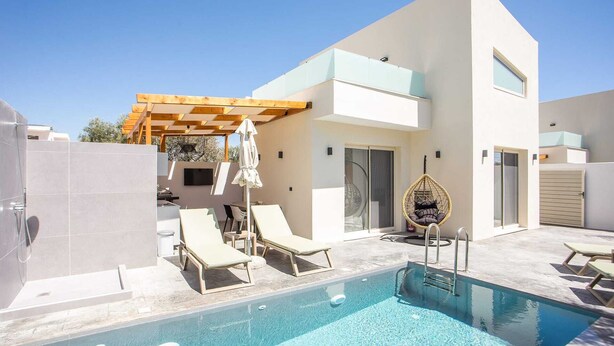 A modern pool area with lounge chairs, a hanging chair, and a pergola. - Aura Luxury Villas Anasa, Villa (Rhodes)