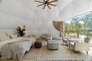 A spacious tent with a bed, seating area, and a ceiling fan. - Spectacular Two Domes and Lofted Cabin Union with Breathtaking Deck and Indoors in Elgin, Texas (Elgin)