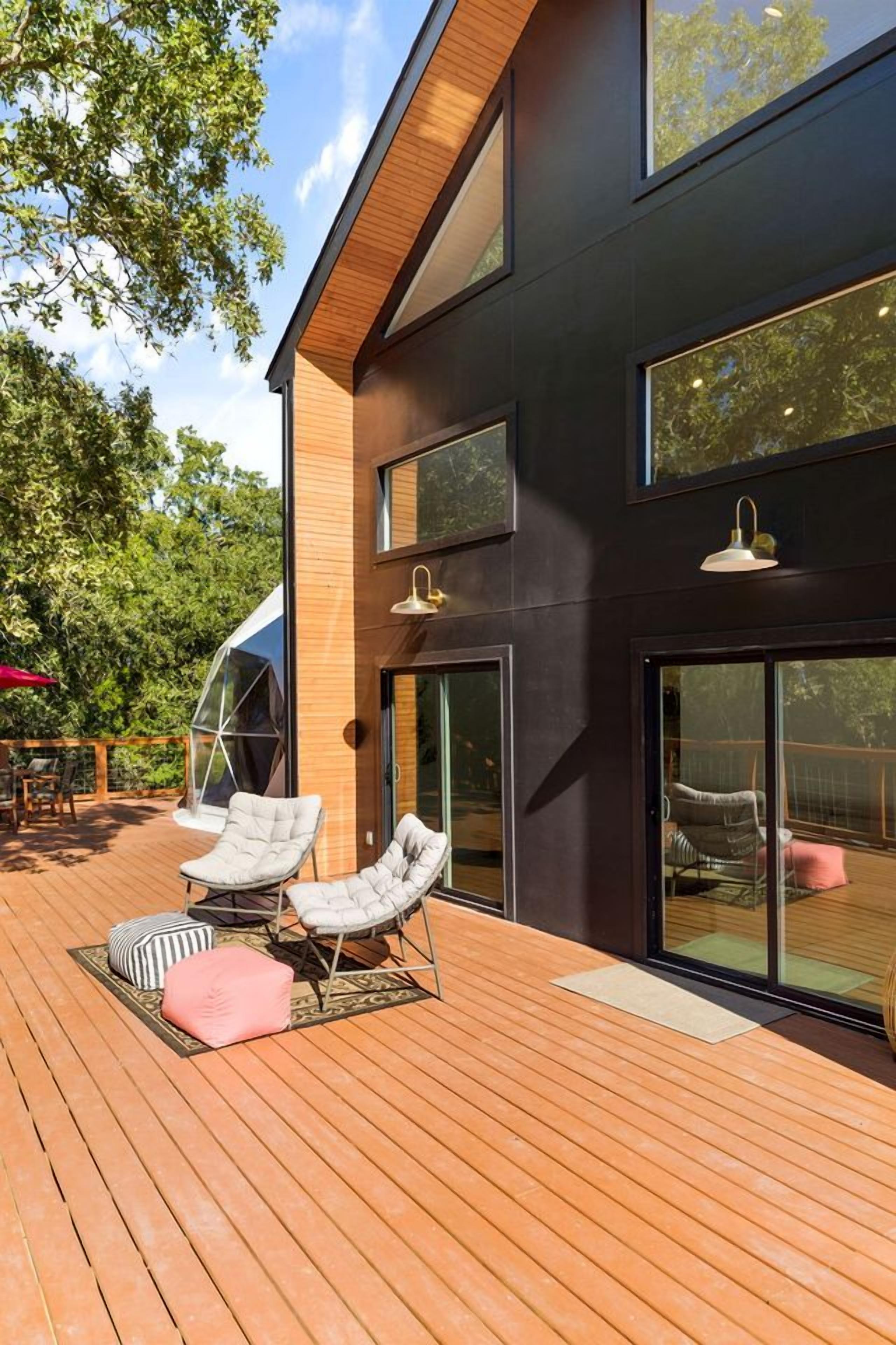 Een modern gebouw met grote ramen, een terras met lounge fauteuils en een glazen entree.