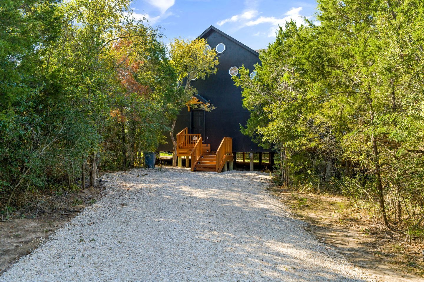 A modern building with a gravel driveway leading to a wooden staircase.