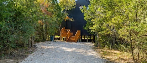 A modern building with a gravel driveway leading to a wooden staircase.