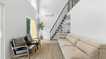A modern interior with a staircase, a sofa, and two chairs.