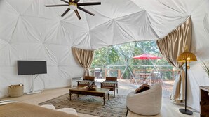 Habitación con carpa, televisión, zona de estar y vistas al exterior.