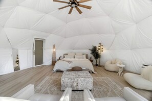 Ein geräumiges Zelt mit einem Bett, einem kleinen Tisch, einem Stuhl und einer Stehlampe.
