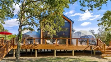 A modern wooden structure with a glass dome, wooden deck, and stairs.