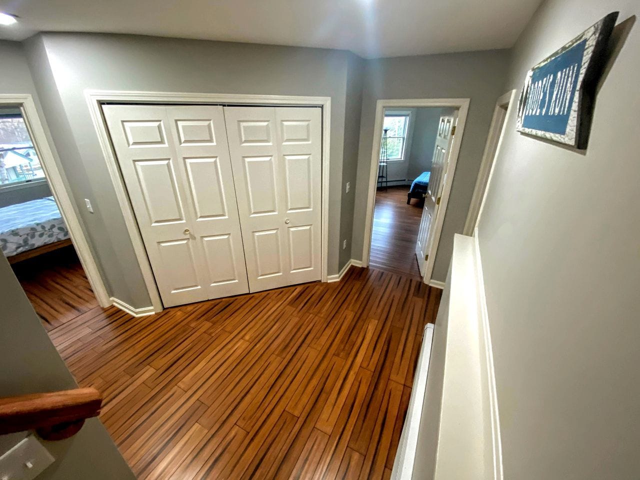 A hallway with wooden flooring, a white door, and a blue sign on the wall.