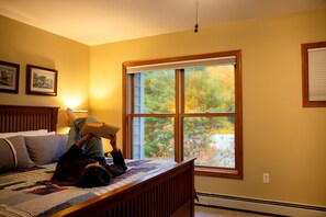 A bedroom with a bed, a window with a view of trees, and a lamp on the nightstand. - Bretton Woods Vacation Rental near Mt Washington (Carroll)
