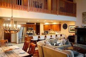 A spacious living area with a high ceiling, a dining table set for four, and a cozy seating area with a fireplace. - Bretton Woods Vacation Rental near Mt Washington (Carroll)