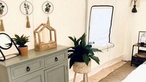 A bedroom with a bed, a dresser, a mirror, and a potted plant.