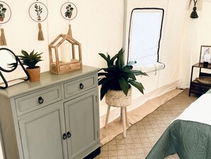 Ein Schlafzimmer mit einem Bett, einem Schminktisch, einem Spiegel und einer Zimmerpflanze.