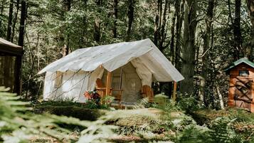 A forested area with a tent-like structure, a wooden chair, and a small building labeled 'The Outhouse.'