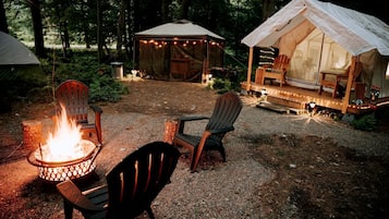 A tented accommodation with a fire pit and seating area.