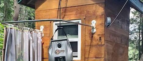 A wooden cabin with a small window, a door, and a metal device mounted on the wall.