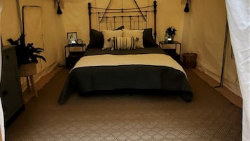 A tented room with a bed, bedside tables, a lamp, and a hanging light fixture.
