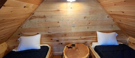 Un dormitorio ático acogedor con dos camas, una mesa de madera en el centro y una lámpara en el techo.