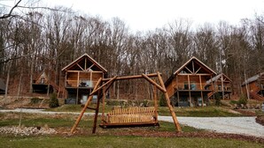 A wooden cabin with a swing set in front, surrounded by trees. - Lofted Cabin Wonderful for Outdoor Adventures near Tappan Lake in Ohio (Deersville)
