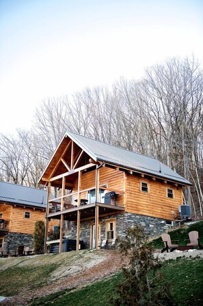 A log cabin with a stone foundation, a balcony, and a metal roof. - Luminous Cabin near Tappan Lake with Hot-Tub, BBQ and Deck in Ohio (Deersville)