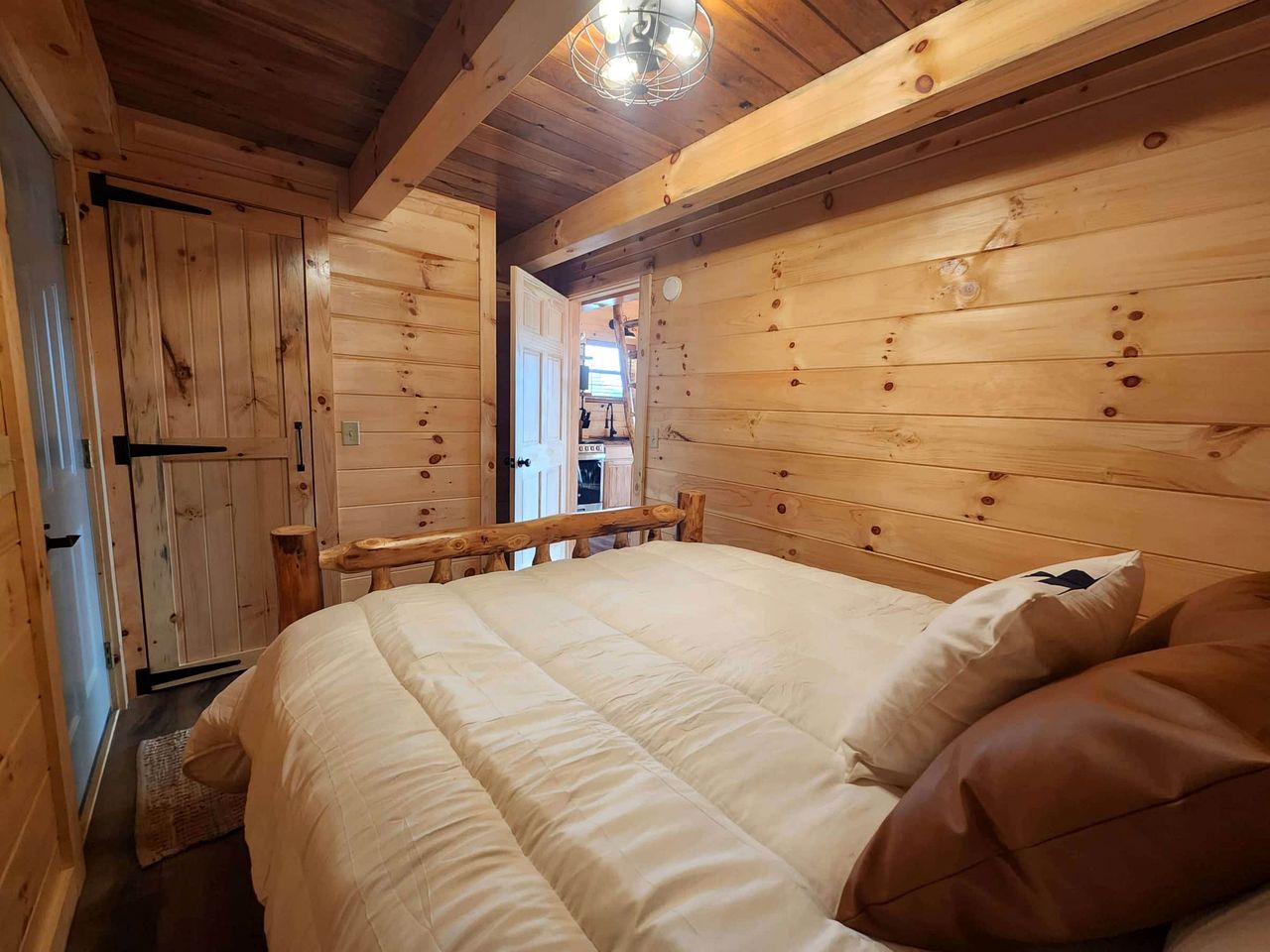 Une chambre dans une cabane en bois, avec un lit, des oreillers et un plafond en bois.