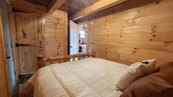Une chambre dans une cabane en bois, avec un lit, des oreillers et un plafond en bois.