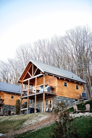Een vakantiehuisje van hout met een stenen fundering, een balkon en een metalen dak.