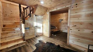 Un intérieur en bois avec un escalier, un tapis en peau de vache et un canapé.