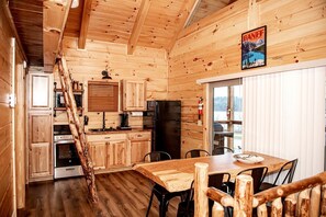 Ein Holzblockhaus-Interieur mit Küche, Essbereich und einer Treppe.