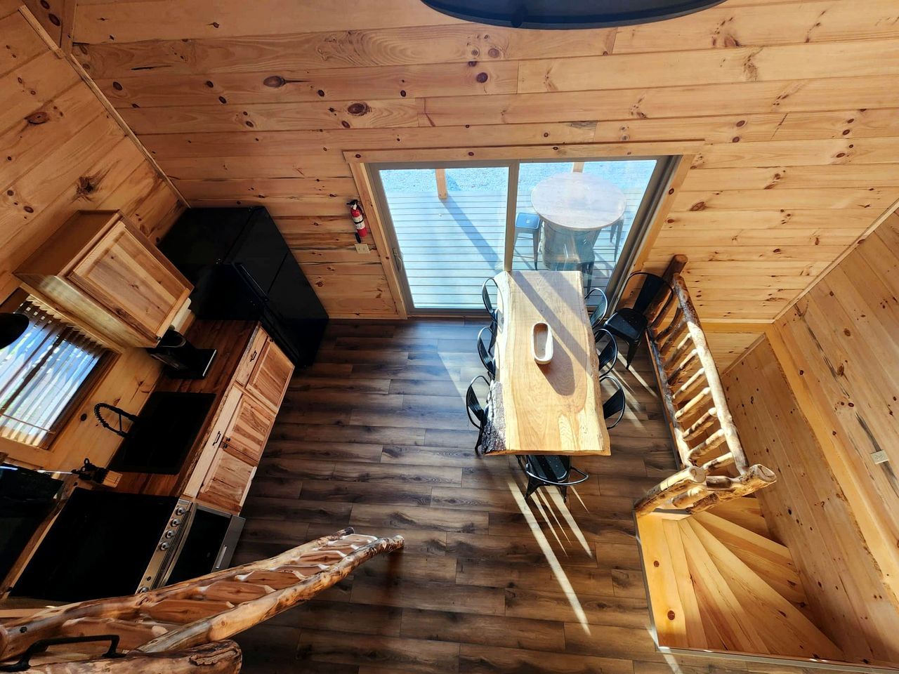 Un interior de madera con una mesa de comedor, zona de cocina y un ventanal amplio.