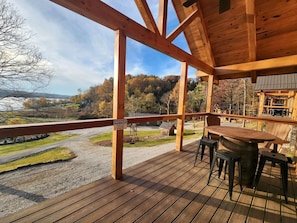 Een houten terras met een tafel en stoelen, uitkijkend op een grindgebied en een weg.