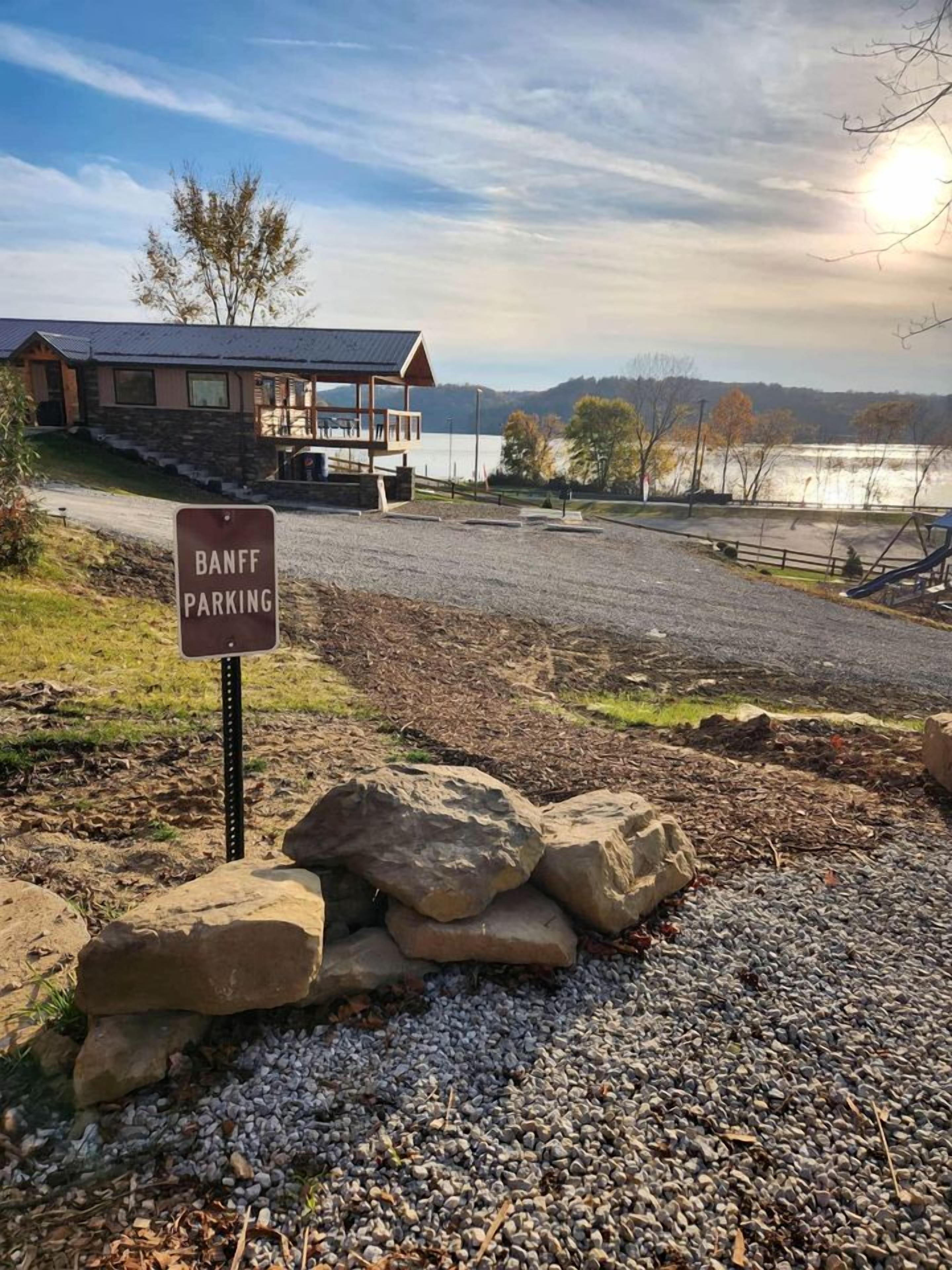 Un edificio de fachada de piedra, un cartel que indica 'BANFF PARKING' y un área de grava en su parte frontal.