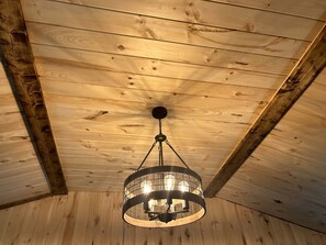 A wooden ceiling with a circular chandelier. - North Carolina Pet-Friendly Cabin Rental for Romantic Getaways to the Mountains (Spruce Pine)
