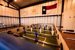 A foosball table in a room with a flag on the wall. - Beautiful Safari Tent Nestled Amidst Trees in San Saba, Texas (San Saba)